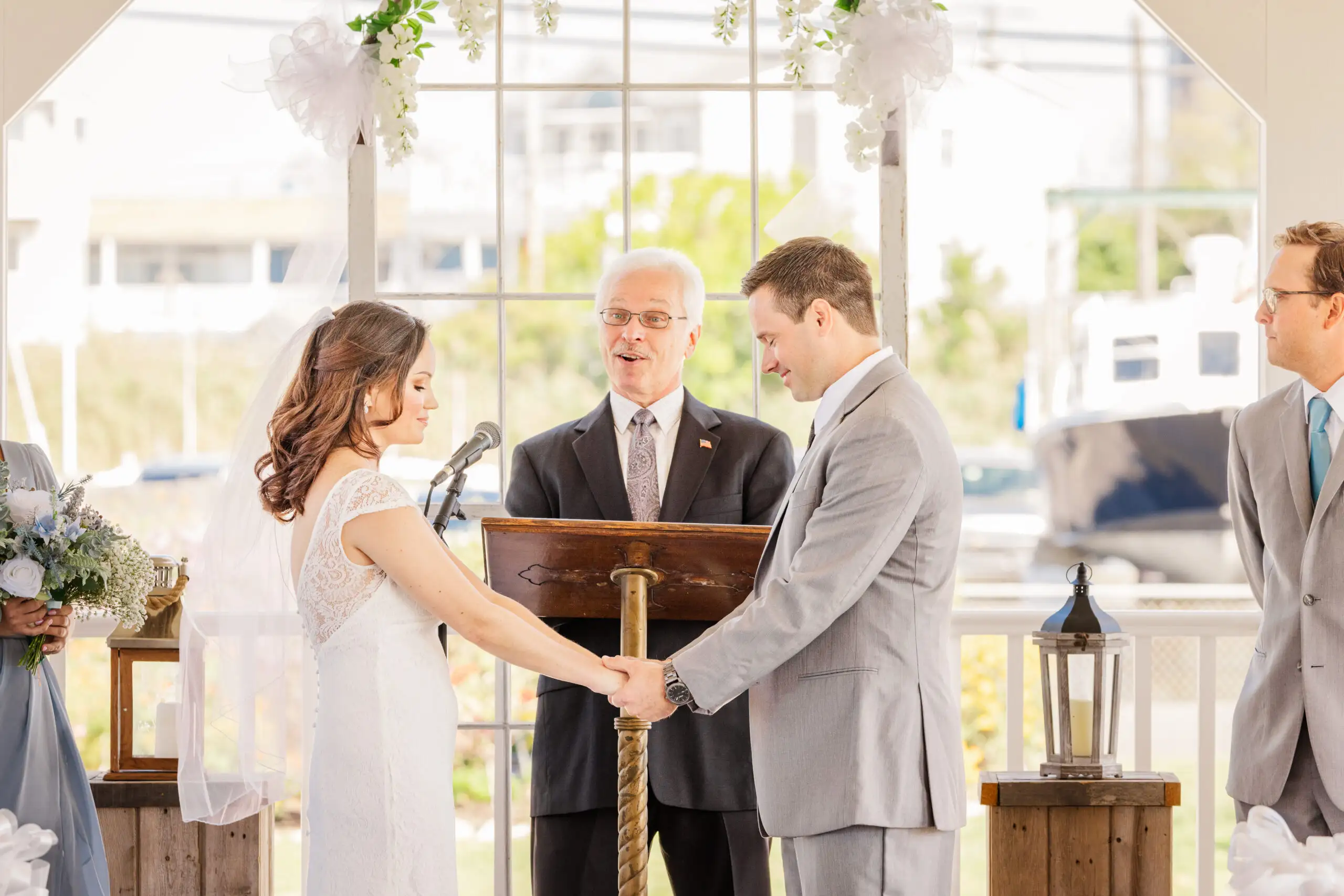 A husband and wife at the alter holding hands listening to the officiant's blessing.