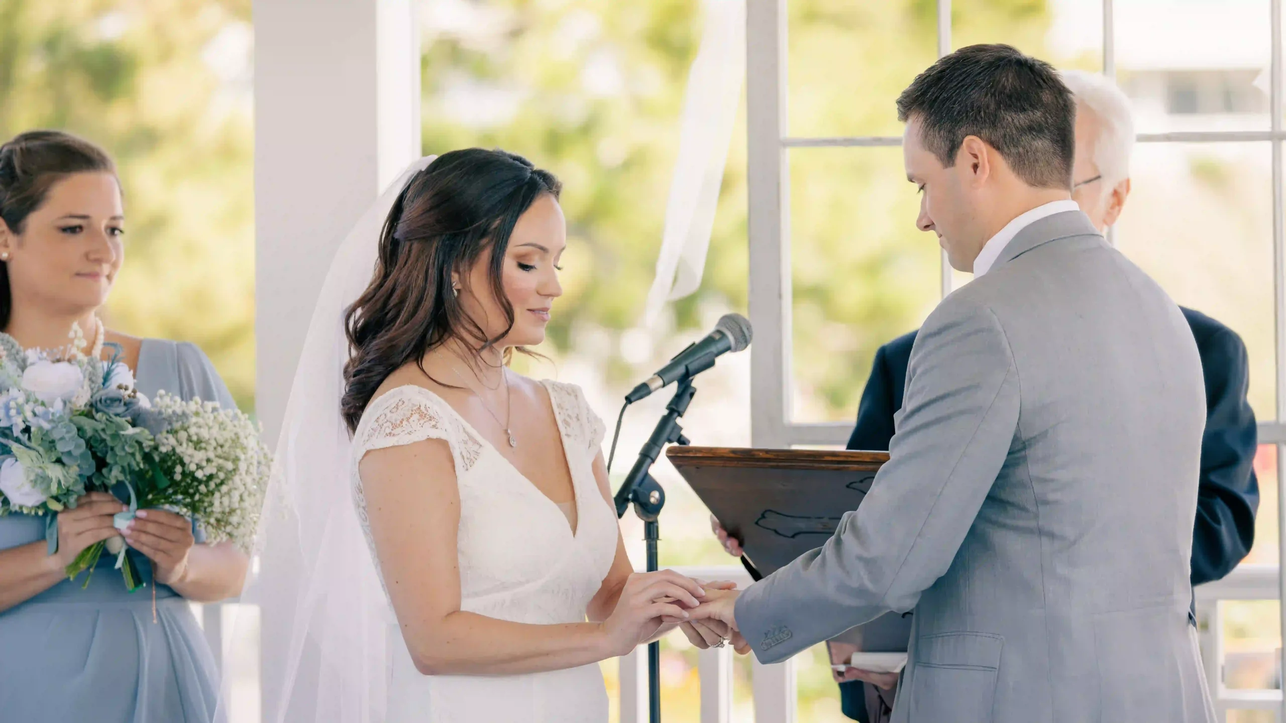 Bride smiles lovingly as she places a wedding ring on the groom's finger during their wedding ceremony at the altar.