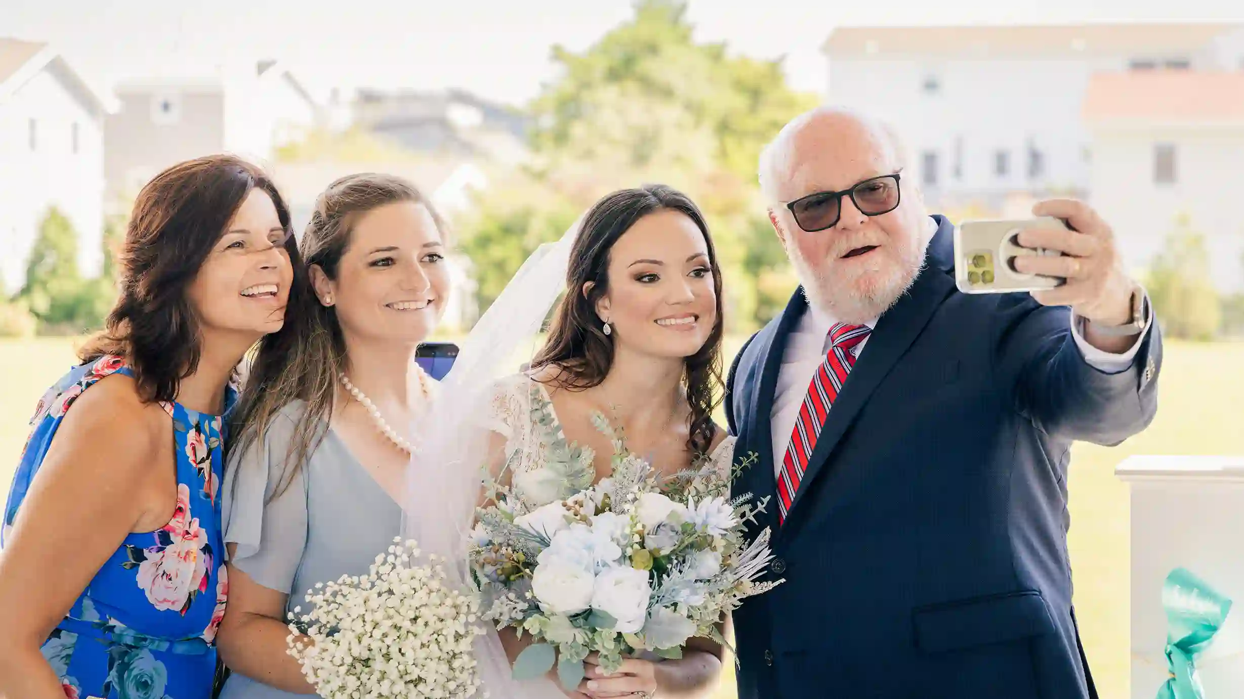 The bride, radiant in her wedding dress, takes a selfie with her close friends. Everyone is laughing and full of joy.