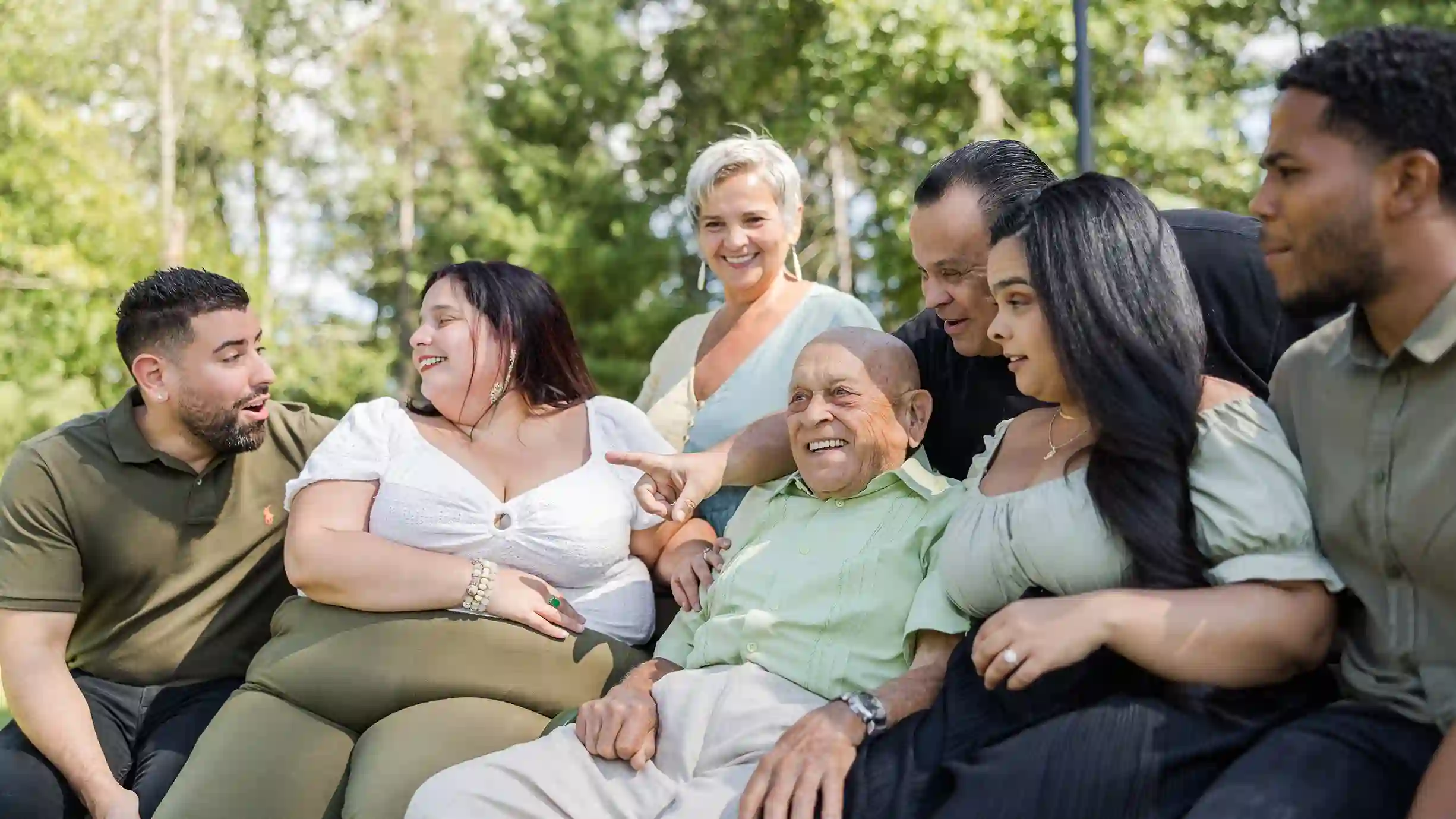 A family photograph aunts, uncles and cousins laughing at a park.