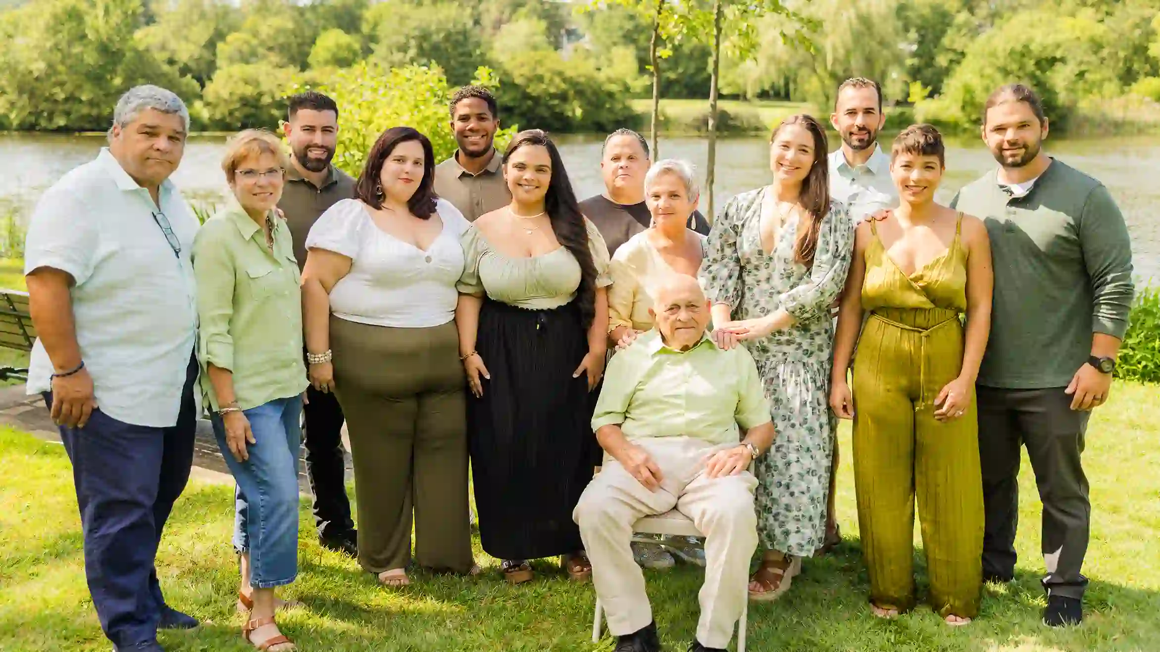 A family photograph during a beautiful sunny day of a grandfather with his niece and nephew at a scenic park with a lake in the background.