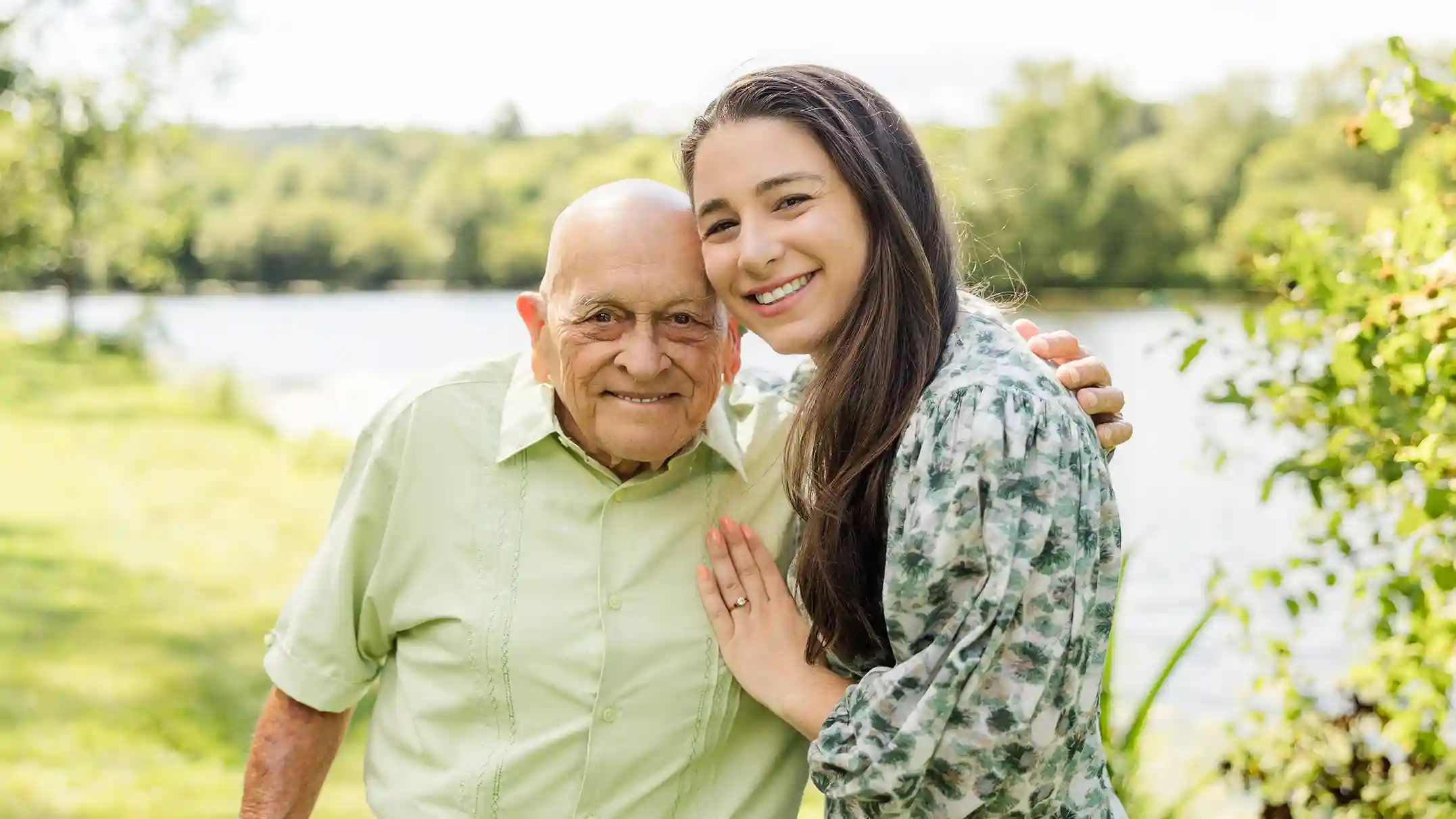 A family photograph of a grandfather with his grand daughter at a scenic park with a lake in the background.