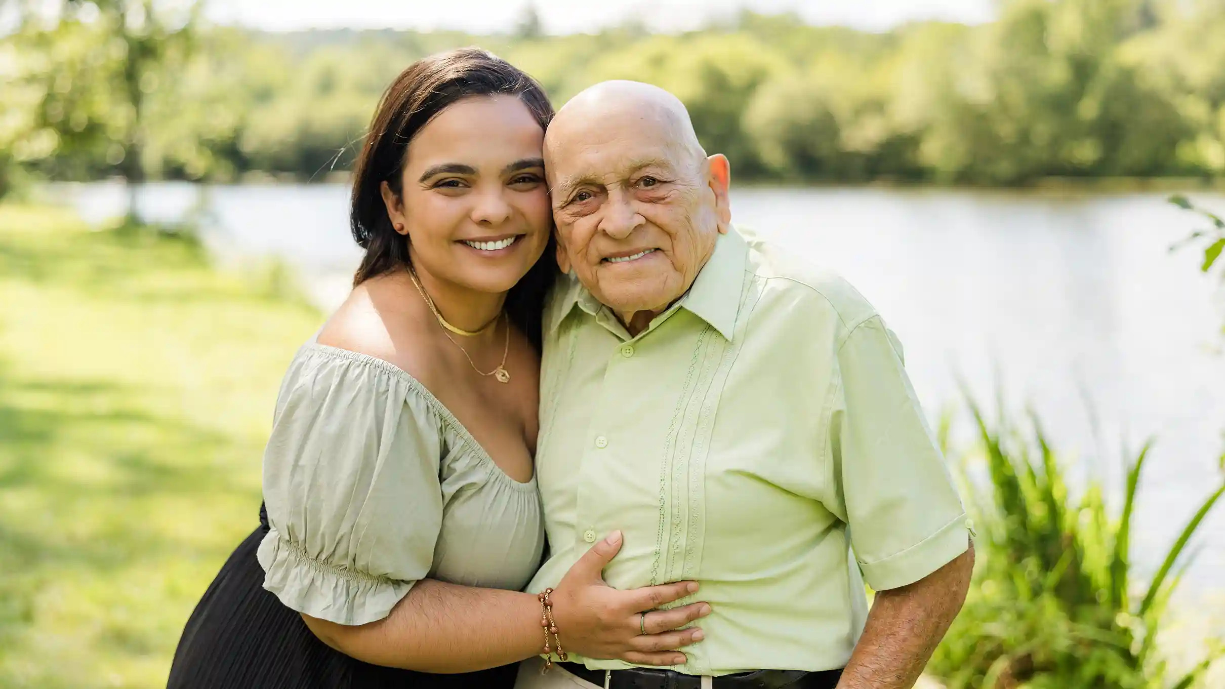 A family photograph of a grandfather with his grand daughter at a scenic park with a lake in the background.