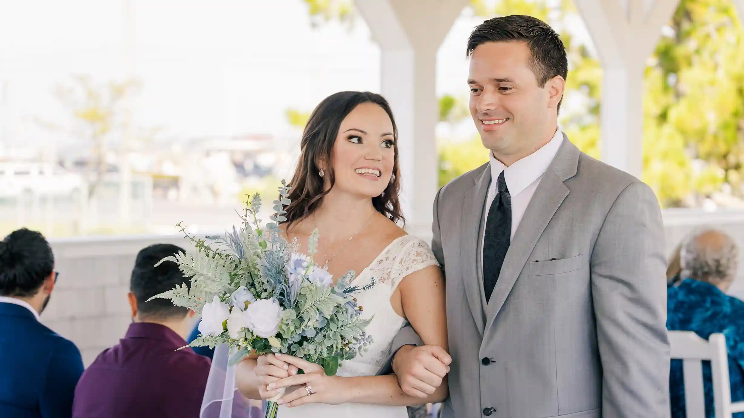 Bride and groom, radiant in their wedding attire, share a loving gaze as they exit the ceremony as husband and wife.