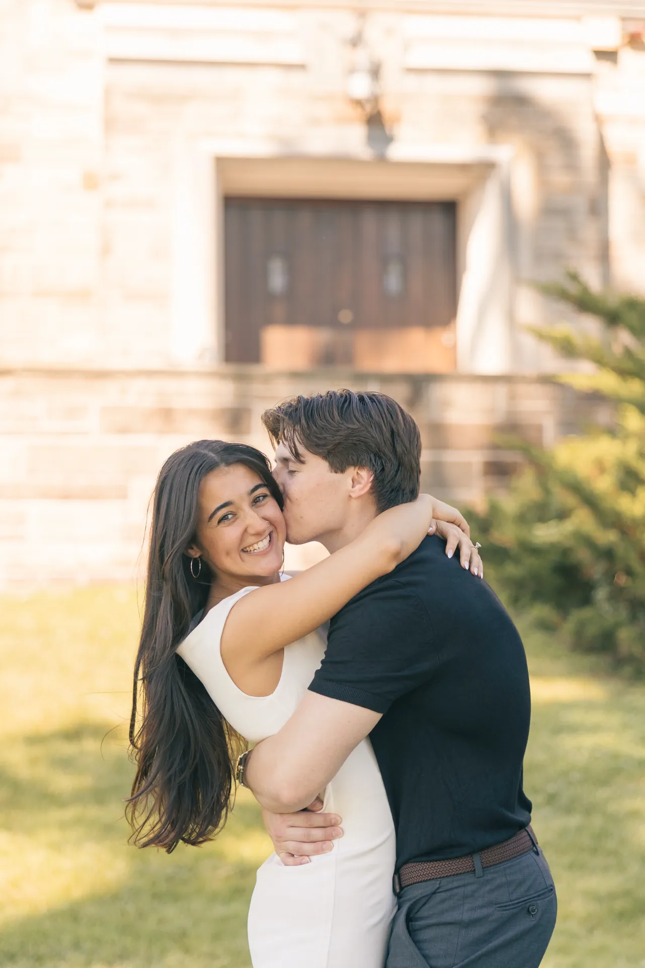 joyful-cheek-kiss-stone-building-engagement
