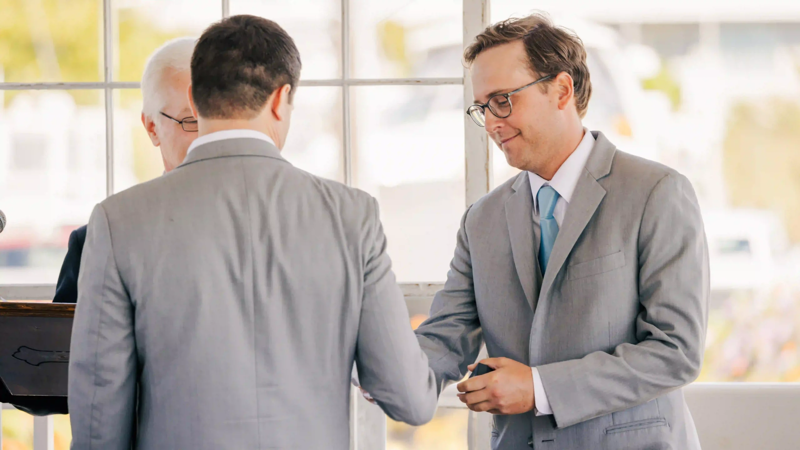 A touching moment as the best man entrusts the wedding rings to the groom.