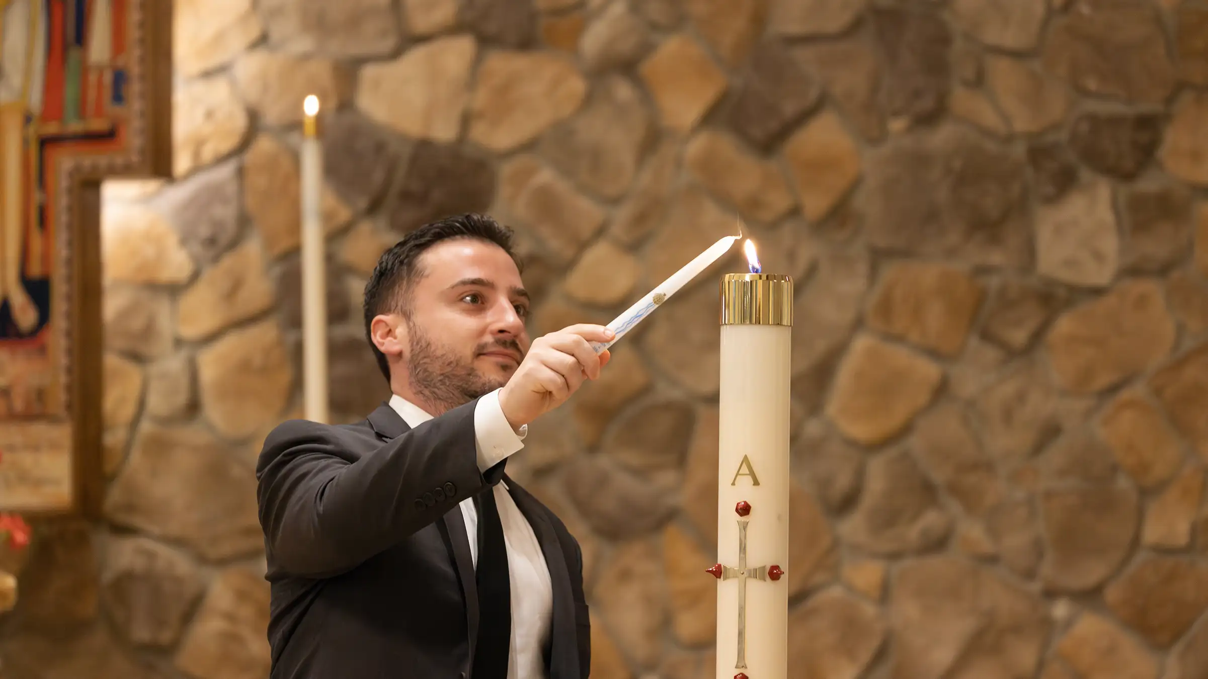 The godfather lighting a candle at the alter during a baptism ceremony.