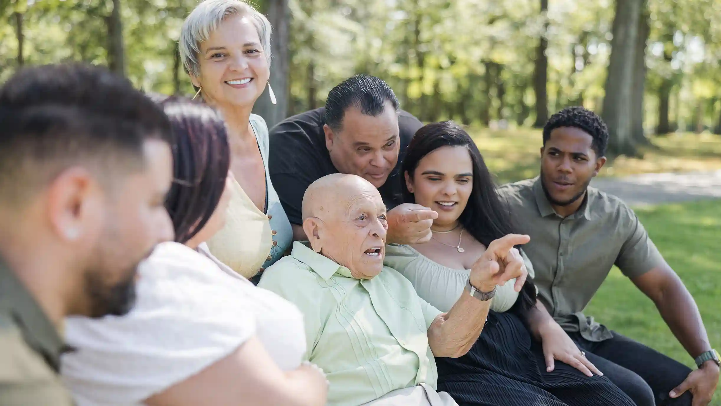 A family photograph aunts, uncles and cousins laughing at a park.