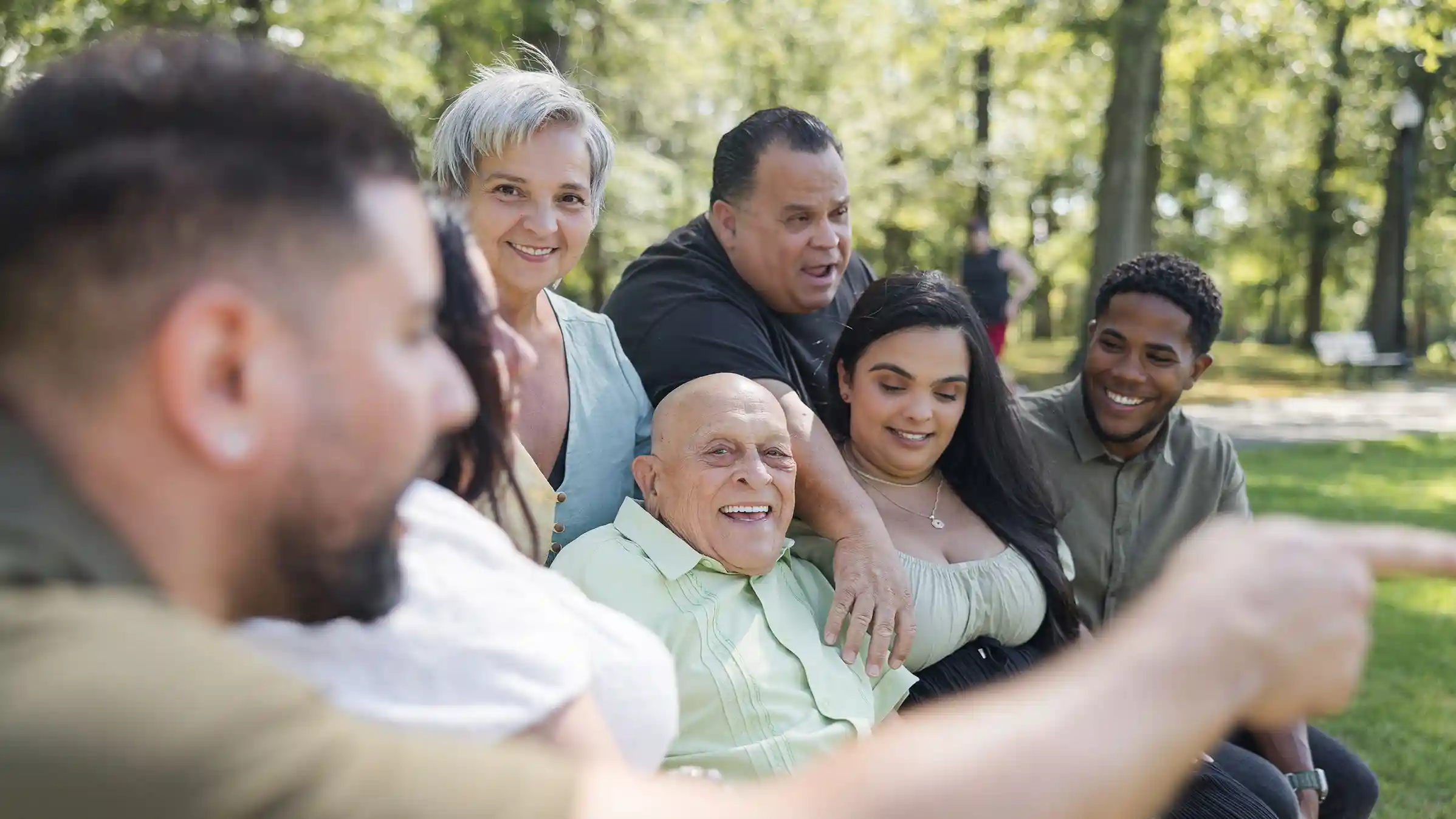 A family photograph aunts, uncles and cousins laughing at a park.