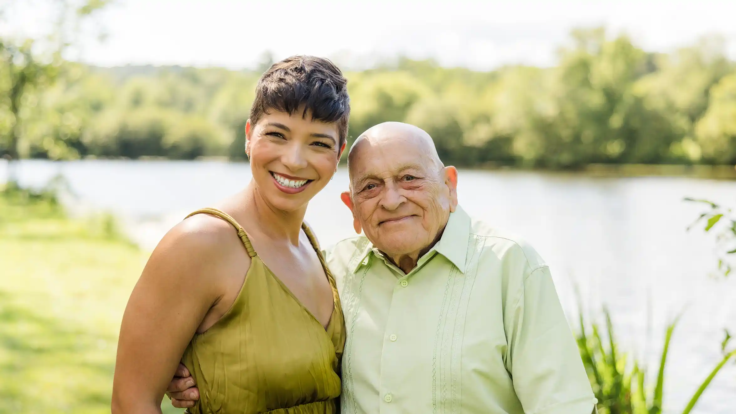 A family photograph of a grandfather with his grand daughter at a scenic park with a lake in the background.