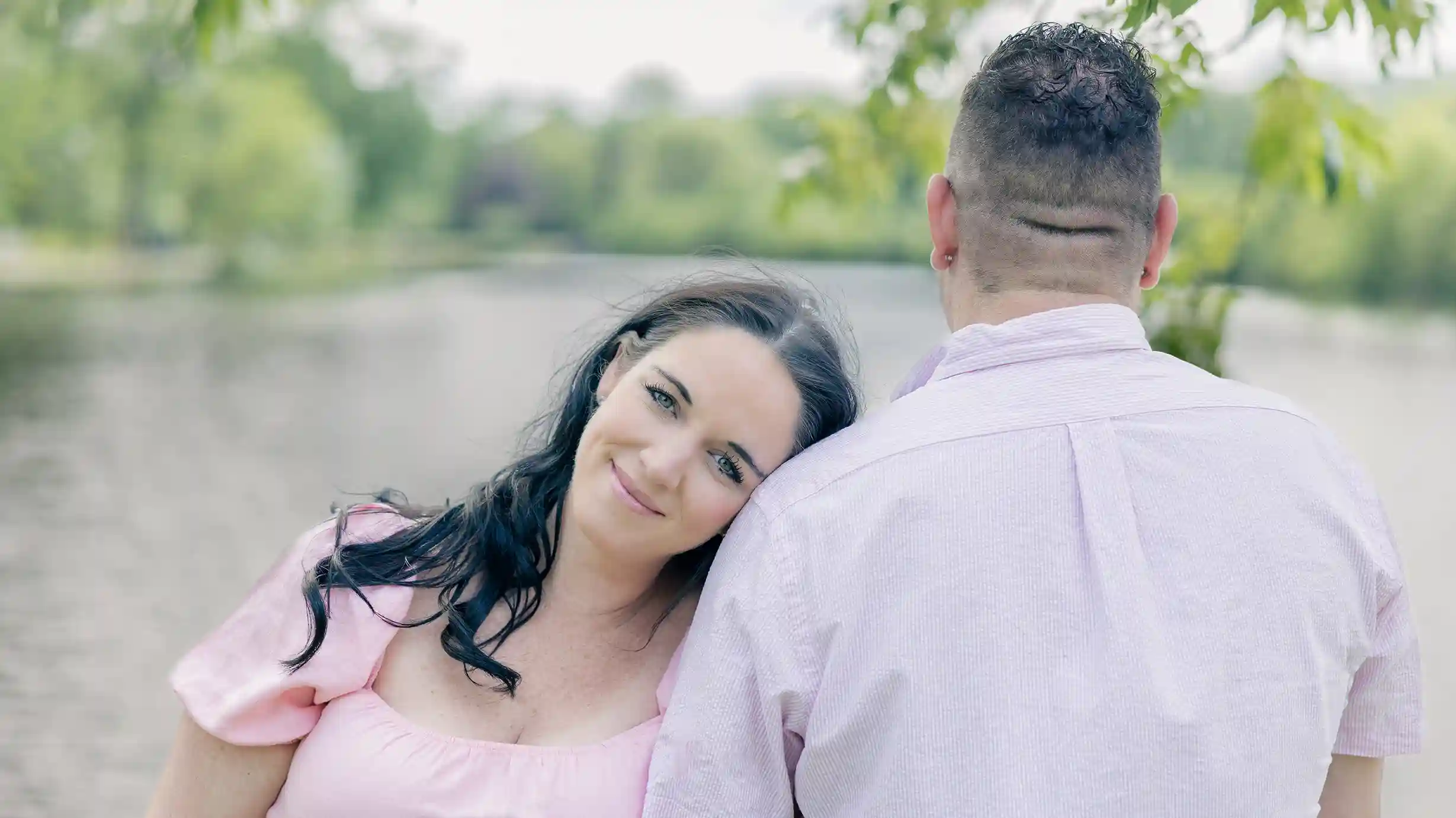 Wife radiates joy while leaning her head on her husband on a beautiful sunny day.