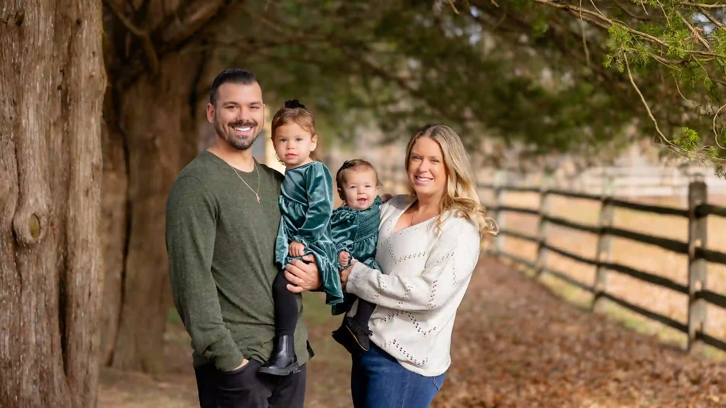 A family smiling at a park during their Christmas tree photoshoot with beautiful bright sun.