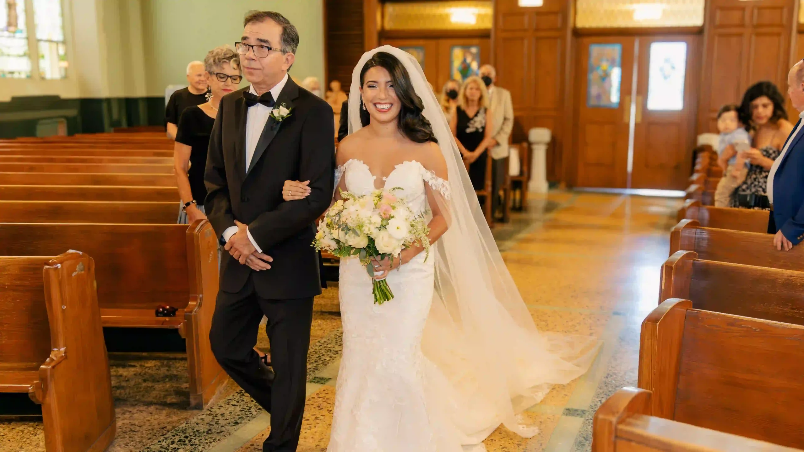 Daughter, radiant in her wedding gown, takes a cherished walk down the aisle with her proud father.