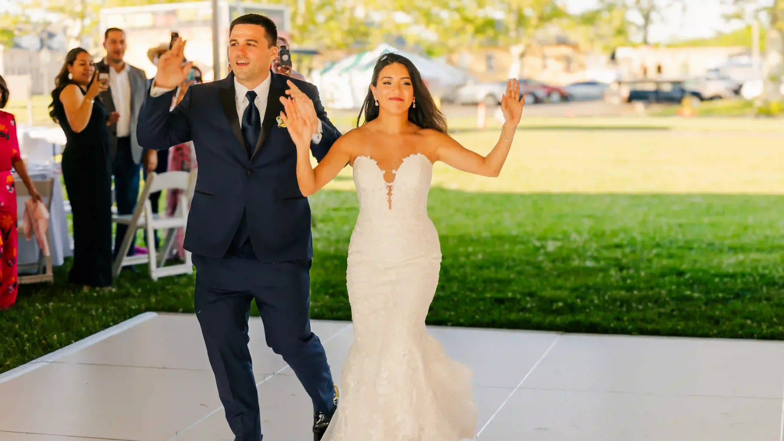 Ecstatic bride and groom share a joyful entrance into their wedding reception, surrounded by happy guests.