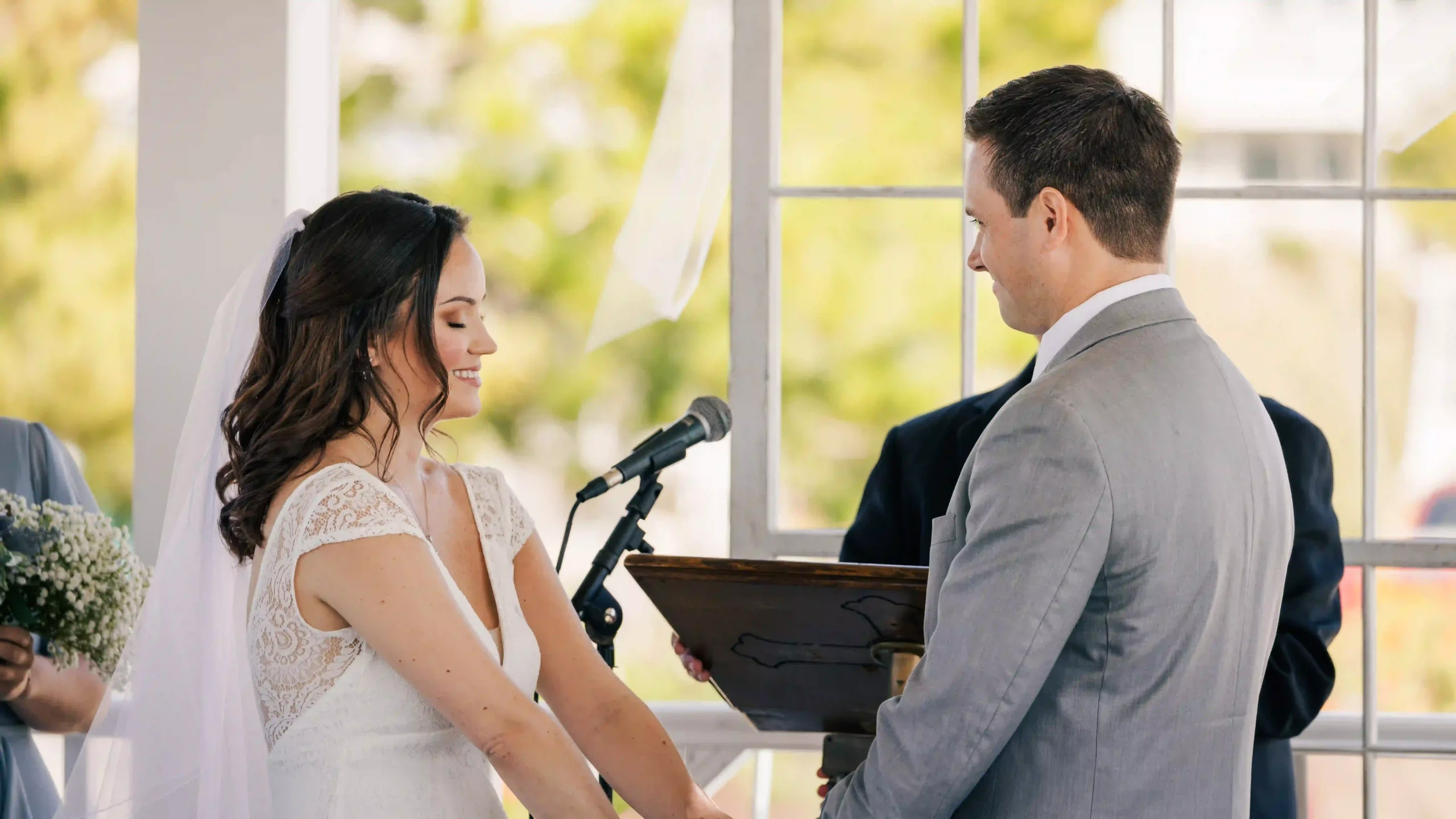 A radiant bride with her eyes closed holding the groom's hands, filled with love at the alter.