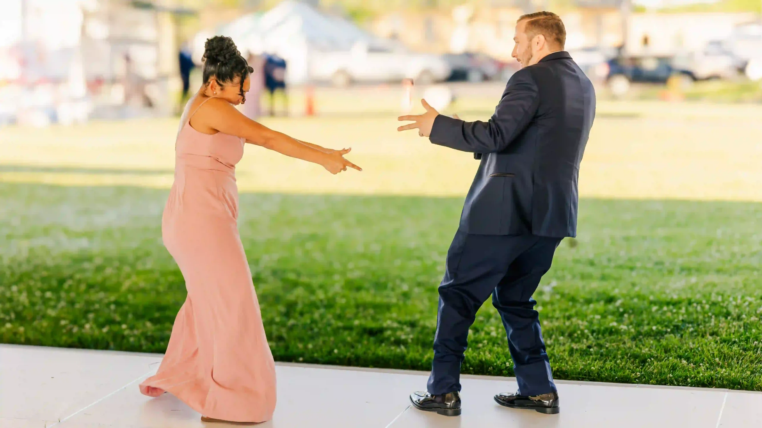 Energetic bridesmaid and groomsman dance their way into the wedding reception pointing fingers at each other.